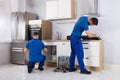 Two Men Checking Induction Stove And Sink Pipe Royalty Free Stock Photo