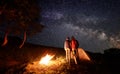 Rear view of two person clinging to each other look at starry sky with milky way