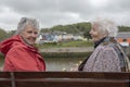 Two senior woman sitting on a park bench outdoors Royalty Free Stock Photo