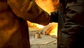 Rear view of two steelmakers at ingot casting shaking hands in front of electric arc furnace in hot shop, metallurgical