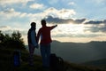 Rear view two tourists are standing on top of mountain against cloudy sky at sunset Royalty Free Stock Photo