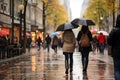 Rear view of two women with umbrellas and waterproof clothing