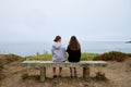 Rear view of two young female friends sitting on a beachside bench Royalty Free Stock Photo