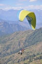 Rear view of unidentified male traveler enjoying paragliding with professional pilot in Himachal Pradesh.