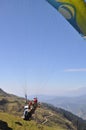 Rear view of unidentified male traveler enjoying paragliding with professional pilot in Himachal Pradesh.