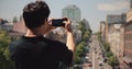 Asian man photographing european city by smartphone