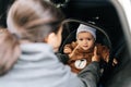 Rear view of unrecognizable young mom placing child safety seat with infant baby boy on back passenger seat. Concept of Royalty Free Stock Photo