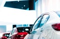 Rear view of white luxury car parked in modern showroom for sale. White shiny car on blurred red car in showroom. Car dealership. Royalty Free Stock Photo