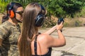 Rear view of white woman and man wearing safety goggles and headphones learning how to operate handgun. Firearms Royalty Free Stock Photo