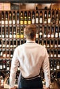 Backside of elegant wine seller selecting wine for customers in wine shop Royalty Free Stock Photo