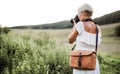 A rear view of woman with camera in nature, taking photographs. Copy space.