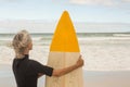 Rear view of woman carrying surfboard while standing against shore Royalty Free Stock Photo