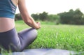 Rear view of a woman doing yoga in nature. A yogi woman sits in a park in a lotus position. Healthy lifestyle and tranquility