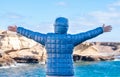 Rear view of a woman enjoying a beautiful winter day at sea, standing on the cliff with outstretched arms. Joyful moment Royalty Free Stock Photo