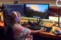 Rear View Of Woman Gaming At Home Eating Potato Chips Sitting At Desk With Monitors