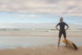 Rear view of woman with hand on hip standing by surfboarda against cloudy sky Royalty Free Stock Photo