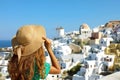 Rear view of woman with hat looking at Oia village in Santorini Island in Mediterranean sea, Greece. Travelling in Europe