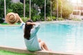 Rear view woman hold a hat sitting in swimming pool, put hands behind head relaxing Summer holidays, vacation, travel concept Royalty Free Stock Photo