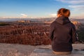 Rear view of woman in hoodie enjoying sunset over unique natural amphitheatre of Bryce Canyon National Park, Utah, USA.