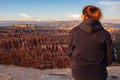 Rear view of woman in hoodie enjoying sunset over unique natural amphitheatre of Bryce Canyon National Park, Utah, USA.