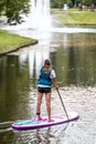 Rear view of a woman in lifevest standing on a paddleboard