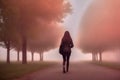 Rear view of a woman with long hair walking along a footpath with an avenue of trees that disappears in the fog, made with