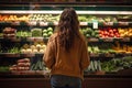 Rear view of woman looking at fresh vegetables on shelf in supermarket, rear view of Young woman shopping for fruits and