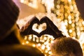 Rear view of woman making heart shape with her hands against house decorated with christmas lights Royalty Free Stock Photo