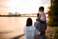 Rear view of woman and man with little girl sitting on his shoulders at sunset. Royalty Free Stock Photo