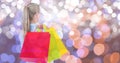 Rear view of woman with multi colored shopping bags over bokeh Royalty Free Stock Photo