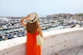 Rear view of woman with orange dress looking Bisceglie port from the old town, Apulia, Italy