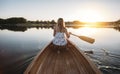 Rear view of woman paddling the canoe on sunset lake Royalty Free Stock Photo