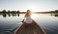 Rear view of woman paddling the canoe on sunset lake Royalty Free Stock Photo