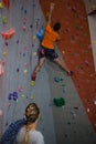 Woman with rope looking at man climbing wall in health club Royalty Free Stock Photo