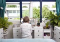 Rear view of woman sitting at dresser in bedroom Royalty Free Stock Photo