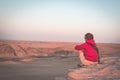 Rear view of woman sitting on rocks and looking at expansive view over the scenic Namib desert at dusk time. Travel in the Namib Royalty Free Stock Photo