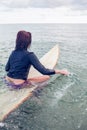 Rear view of a woman sitting on surfboard in water