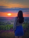 Rear view of a woman in skirt watching the sunset over the valley. Natural summer dusk scene Royalty Free Stock Photo