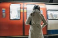 Rear view of a woman standing on a London Underground station platform, moving train on the background Royalty Free Stock Photo