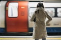 Rear view of a woman standing on a London Underground station platform, moving train on the background Royalty Free Stock Photo