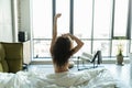 Rear view of young woman stretching in bed after wake up in morning with sunlight Royalty Free Stock Photo