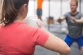 Rear view of woman throwing medicine ball towards man in crossfit gym Royalty Free Stock Photo