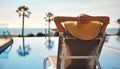 Rear view woman wear hat lying on deckchair on poolside Royalty Free Stock Photo