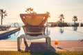 Rear view woman wear hat sunbathing on deckchair on poolside Royalty Free Stock Photo