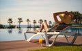 Rear view woman wear hat sunbathing on deckchair on poolside Royalty Free Stock Photo