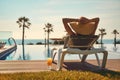 Rear view woman wear hat sunbathing on deckchair on poolside Royalty Free Stock Photo