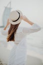 Rear view of a woman wearing casual clothes and straw hat while standing by the sea Royalty Free Stock Photo