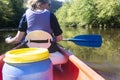 Rear view of a woman wearing a life jacket paddling a canoe down a river in europe Royalty Free Stock Photo