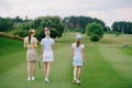 rear view of women in caps with golf equipment walking Royalty Free Stock Photo