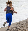 Rear view of women running on beach with cell phone strapped to arm